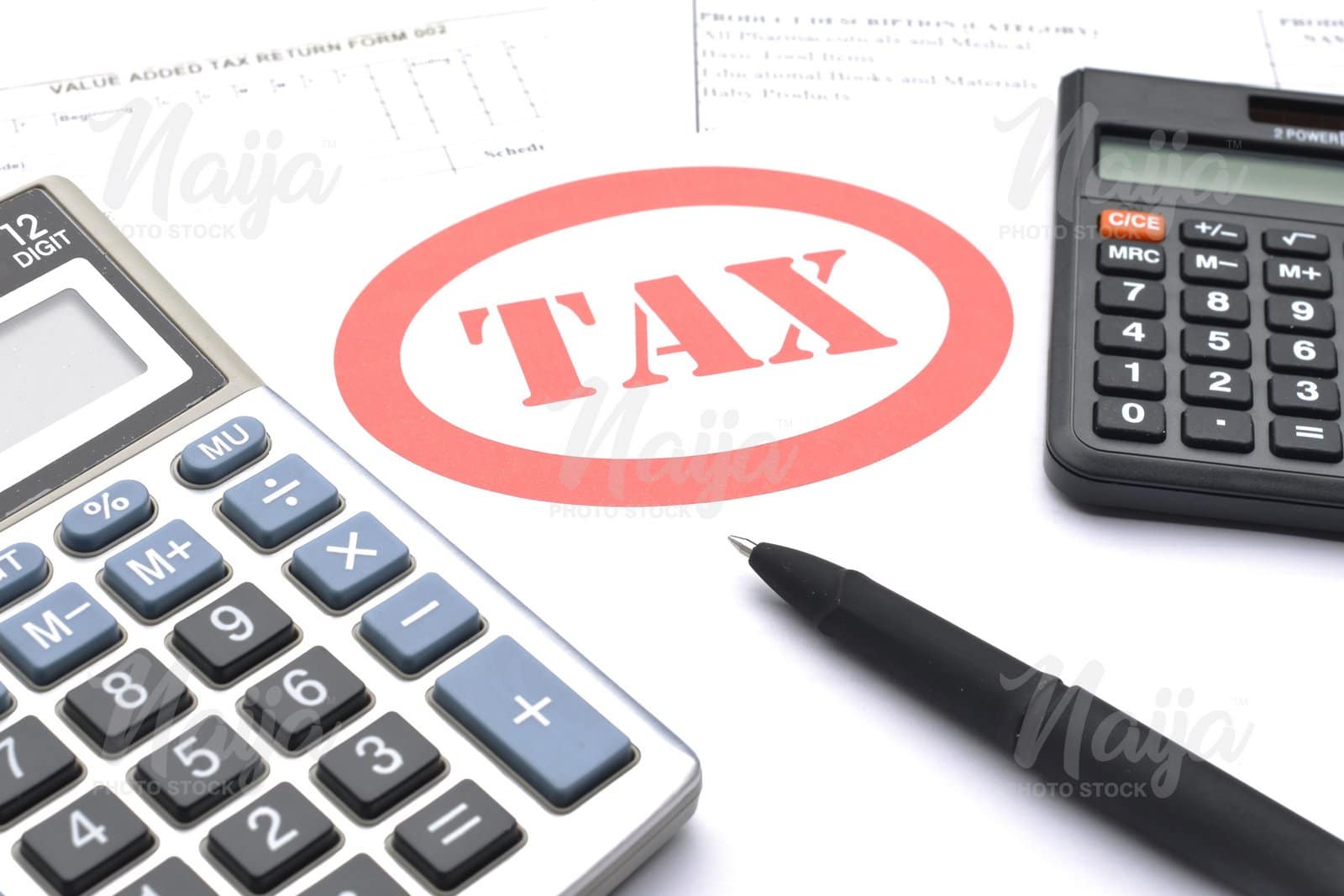 TAX PRINTED ON A WHITE PAPER WITH TWO CALCULATORS AND A PEN